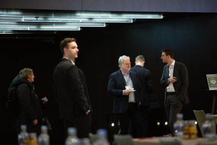 a group of men standing in the conference room and chatting