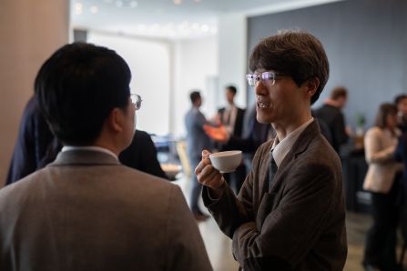 Two people chatting, one of them holding a cup of coffee
