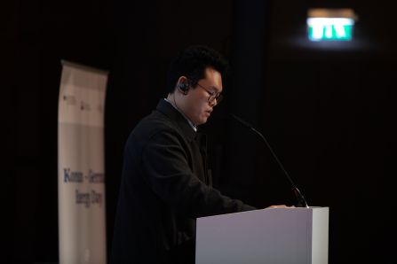 Speaker presenting from the side with rollup in background